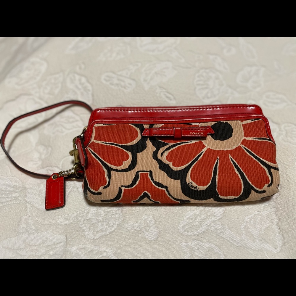 Coach brand orange/cream floral wristlet wallet.